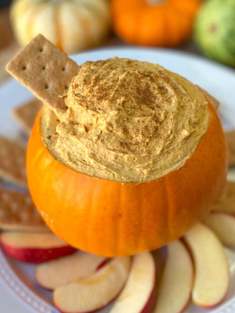 Pumpkin Dip in pumpkin with apple slices and graham cracker