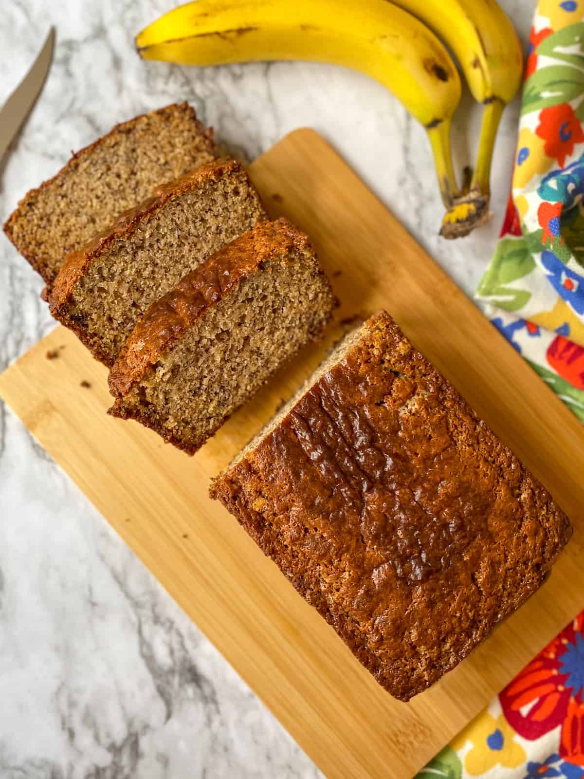 A loaf of banana bread on a cutting board with 3 slices cut