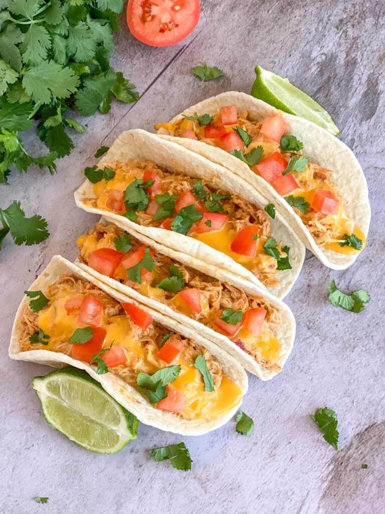4 tacos with tomatoes, limes, and cilantro