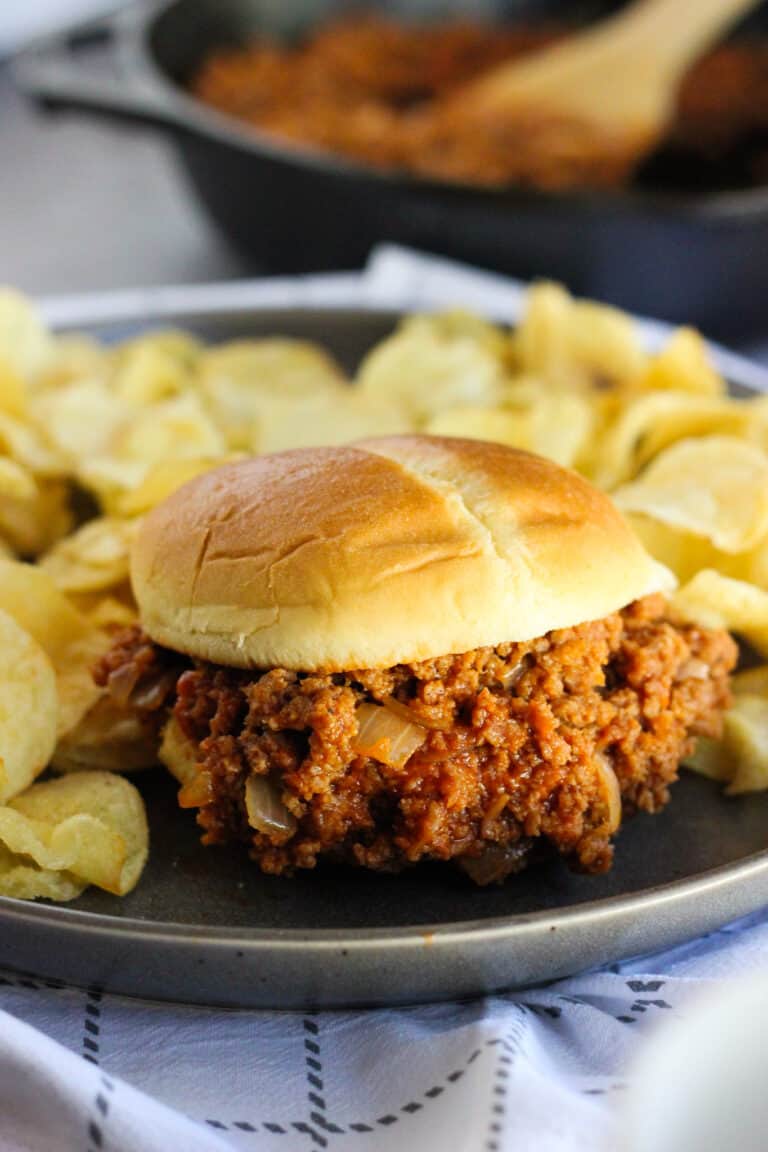 turkey sloppy joe sandwich on a plate with chips and skillet in background