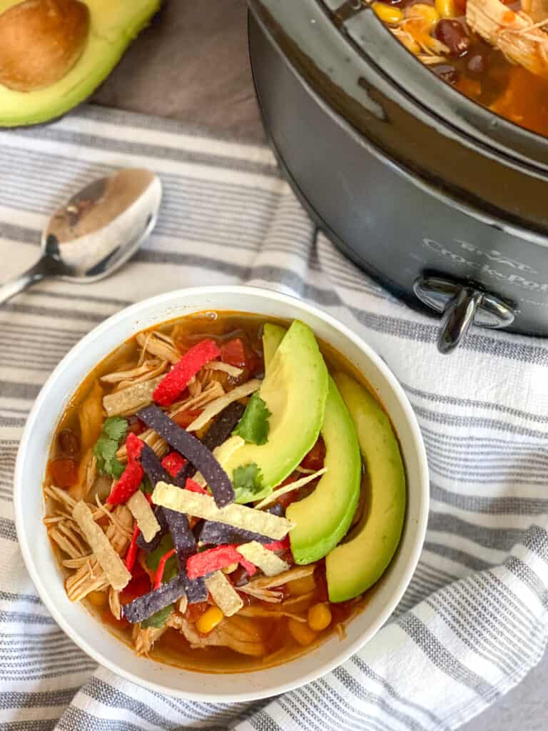 soup in a bowl, in the slow cooker, and a spoon