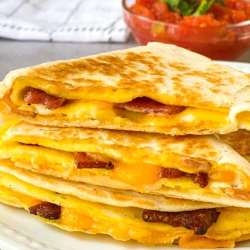 breakfast quesadillas on a white plate, salsa in background