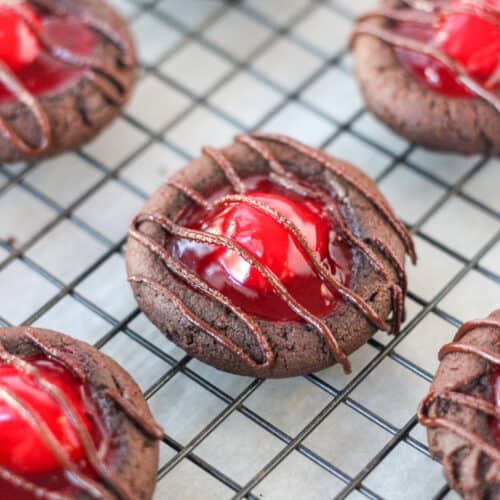 close up of chocolate cherry thumbprint cookies on a cooling rack
