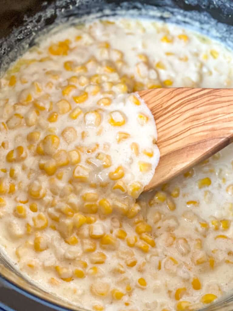 a wooden spoon in a crockpot full of creamed corn