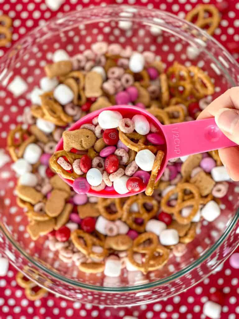 a scoop of valentine sweet and salty snack mix with the bowl in the background