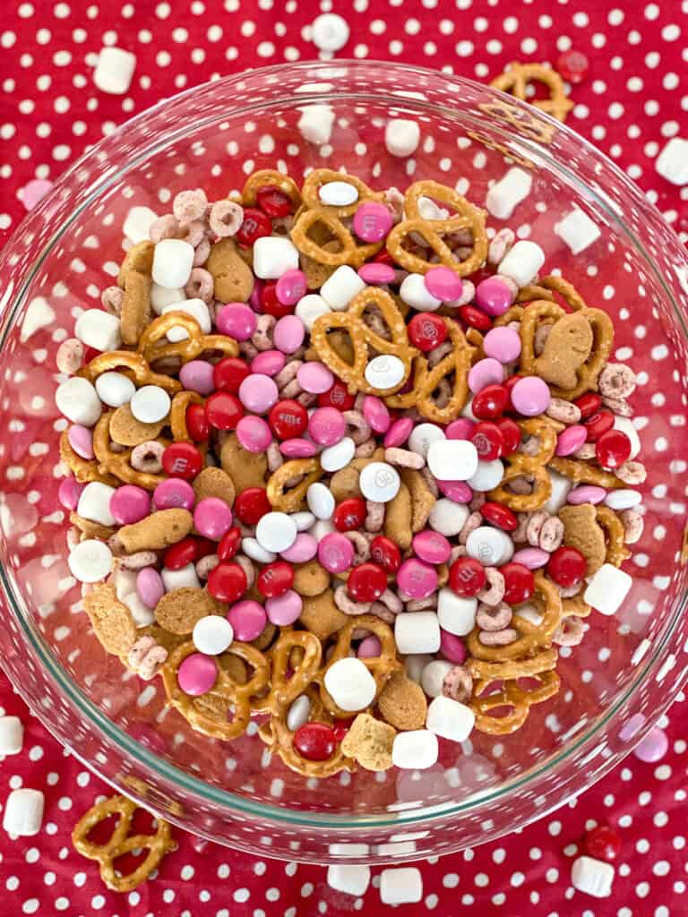 bowl of valentine sweet and salty snack mix in a bowl with a few spilled on the table