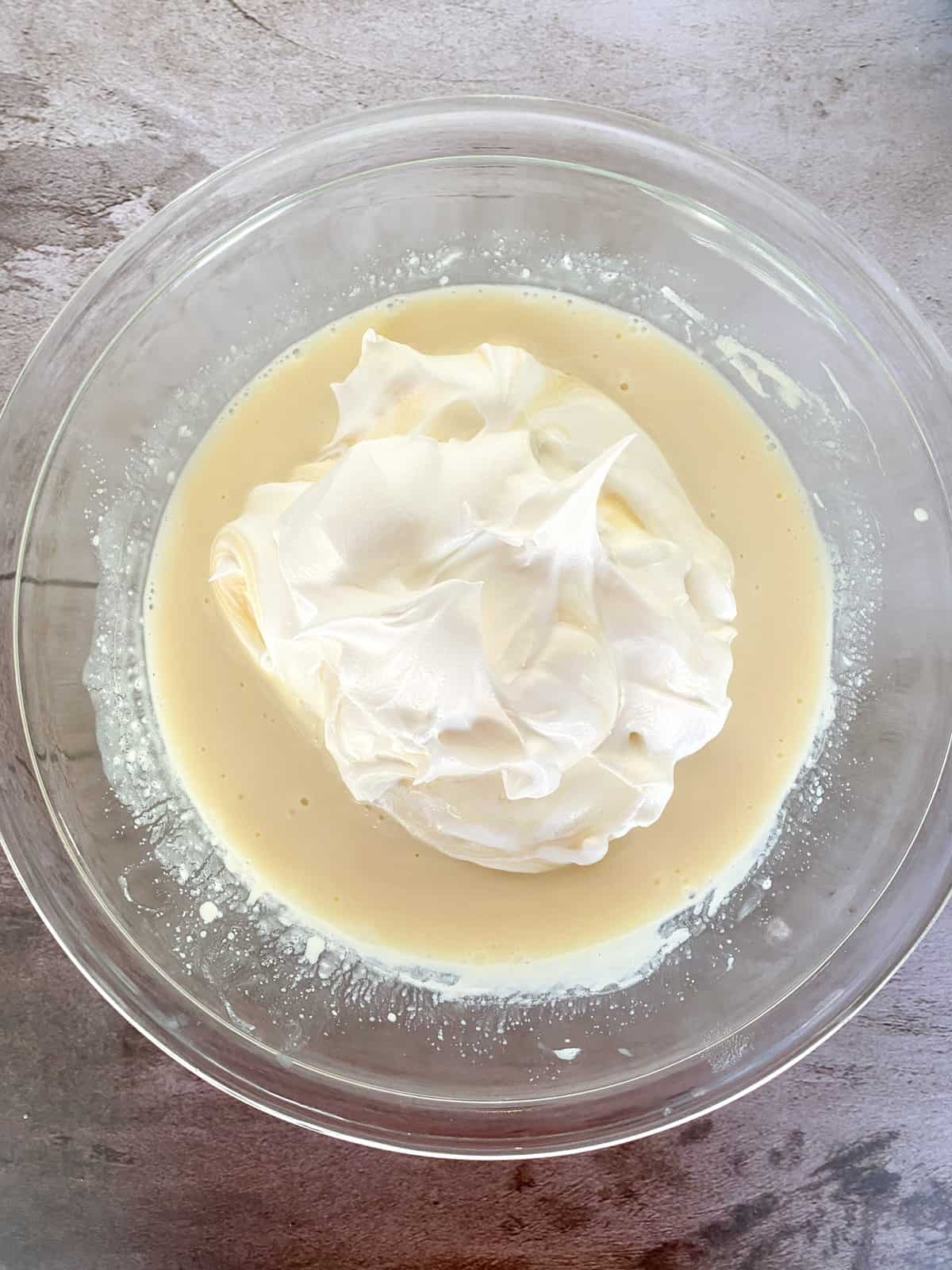 whipped cream on top of lemon mixture in a bowl