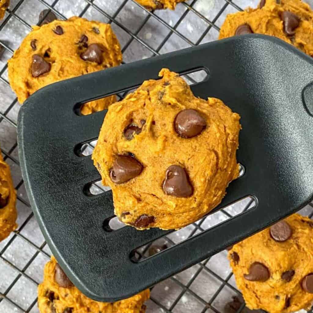 3 Ingredient Pumpkin Spice Cake Mix Cookie on a spatula with more cookies in the background
