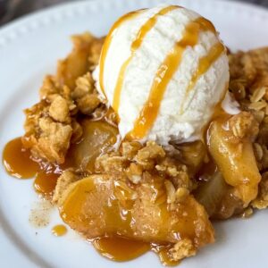 plate of caramel apple pear crisp with ice cream and caramel drizzled on top