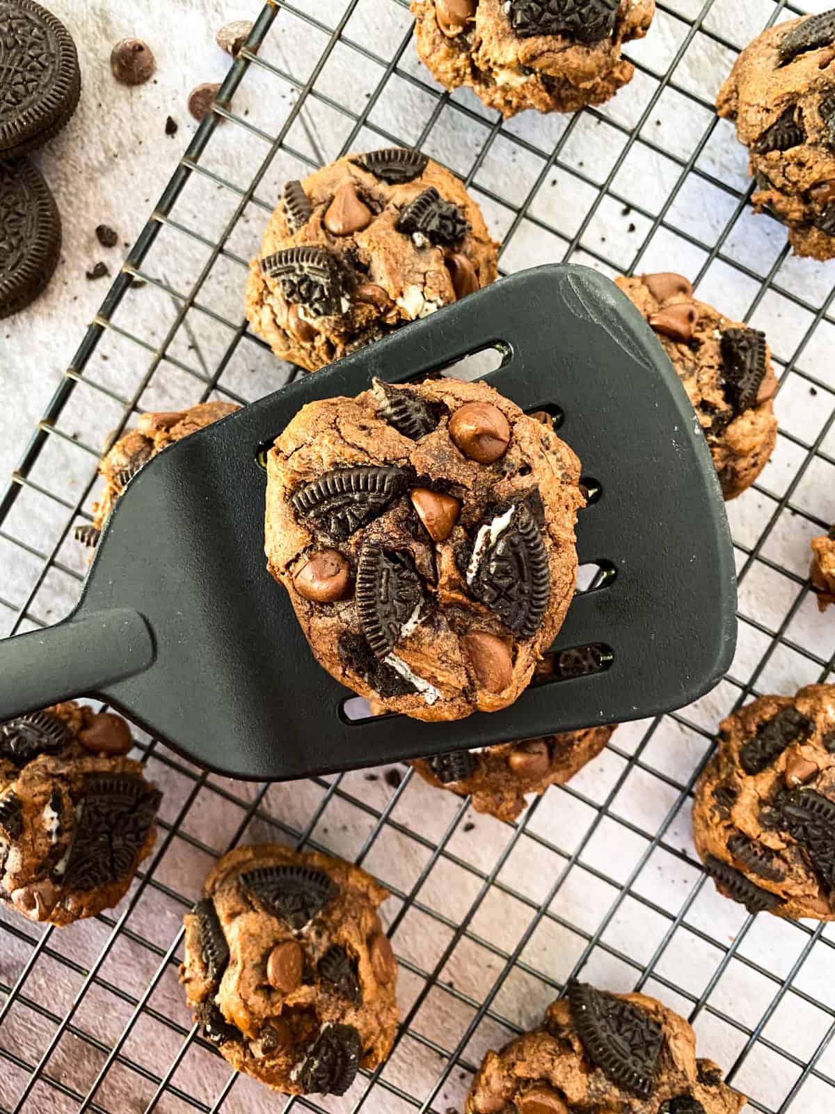 a cookie on a spatula with more cookies on a cooling rack in the background