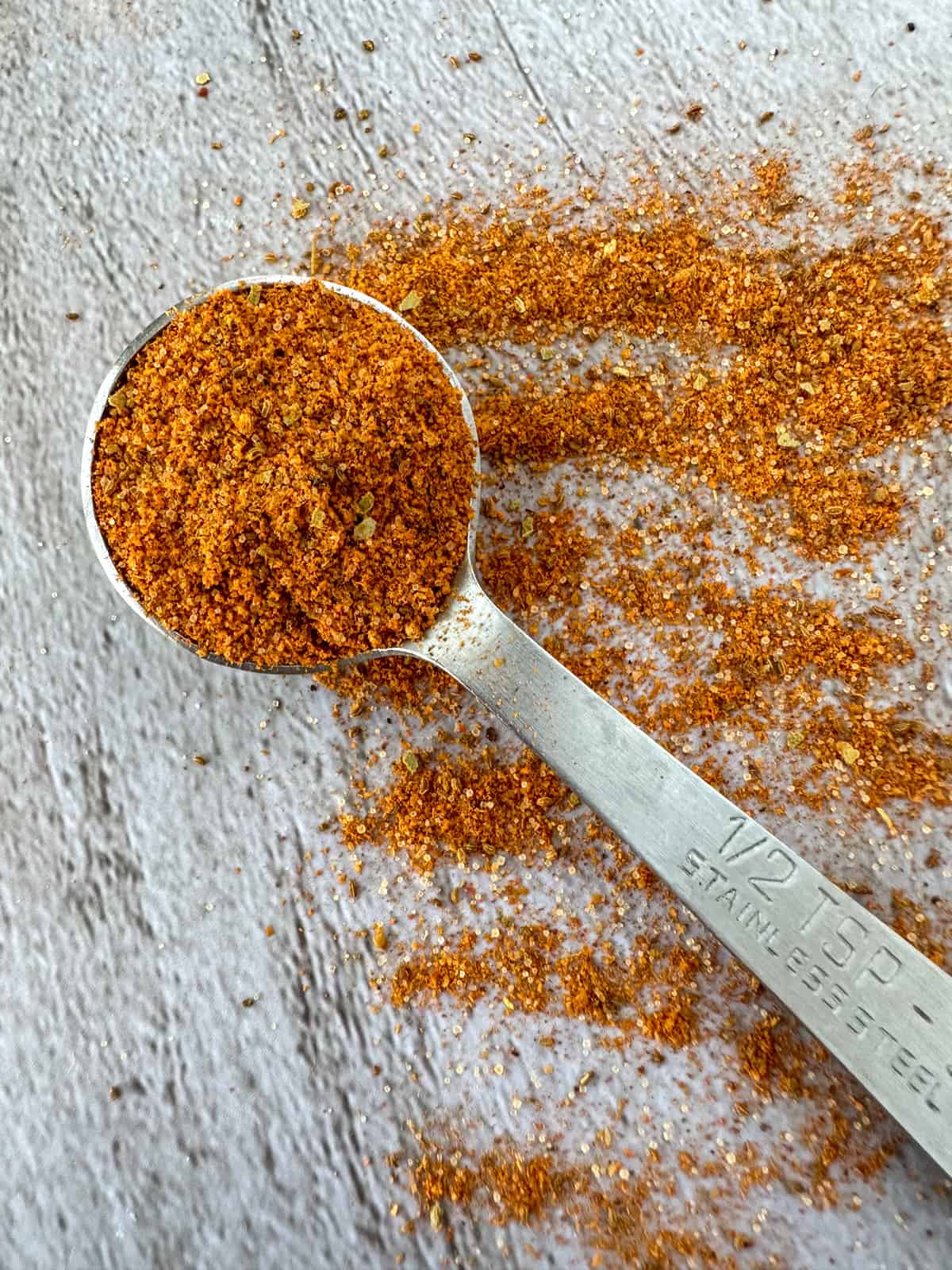 old bay seasoning in a measuring spoon and spilled on a table