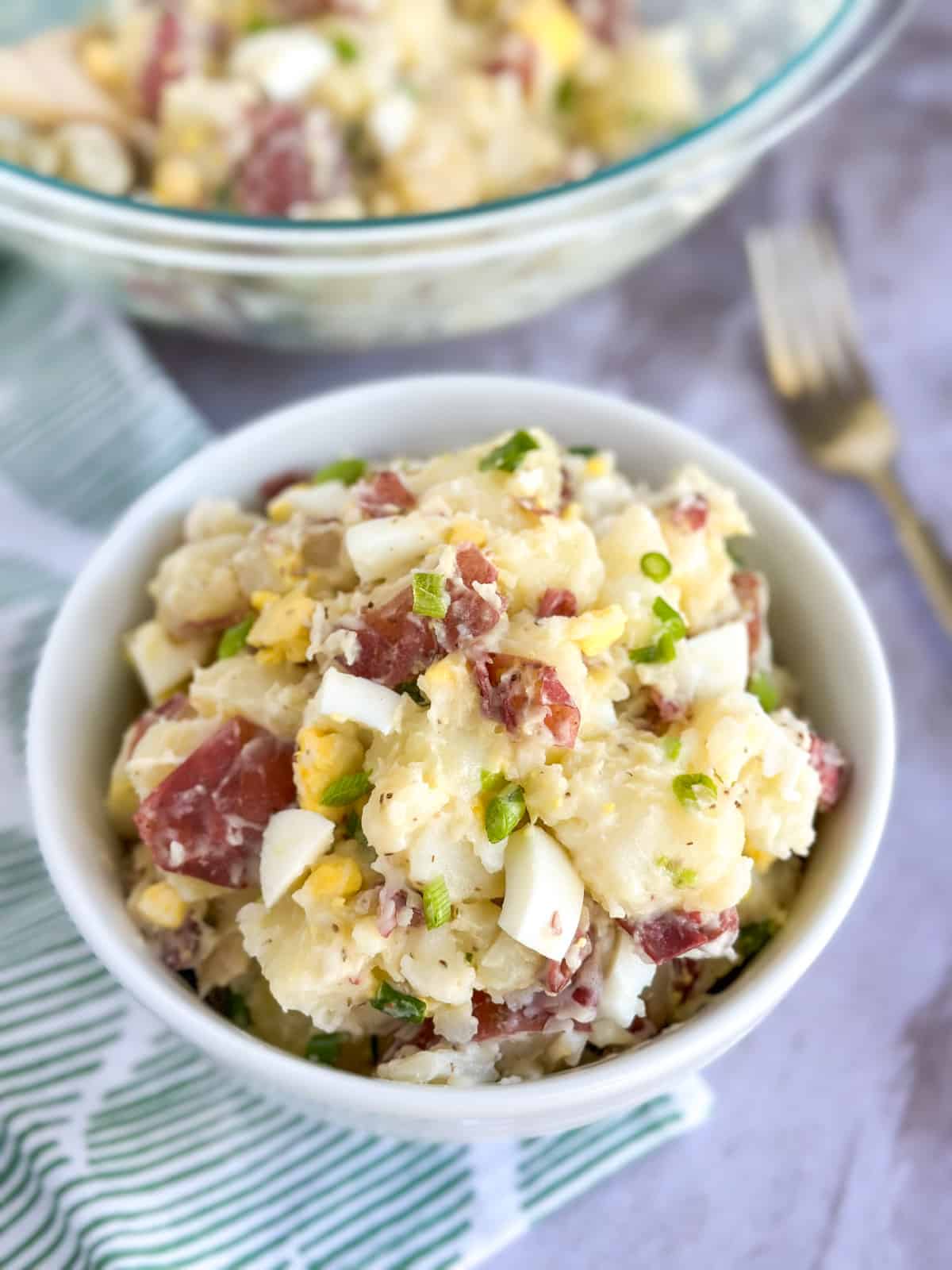 side view of potato salad in a small and large bowl