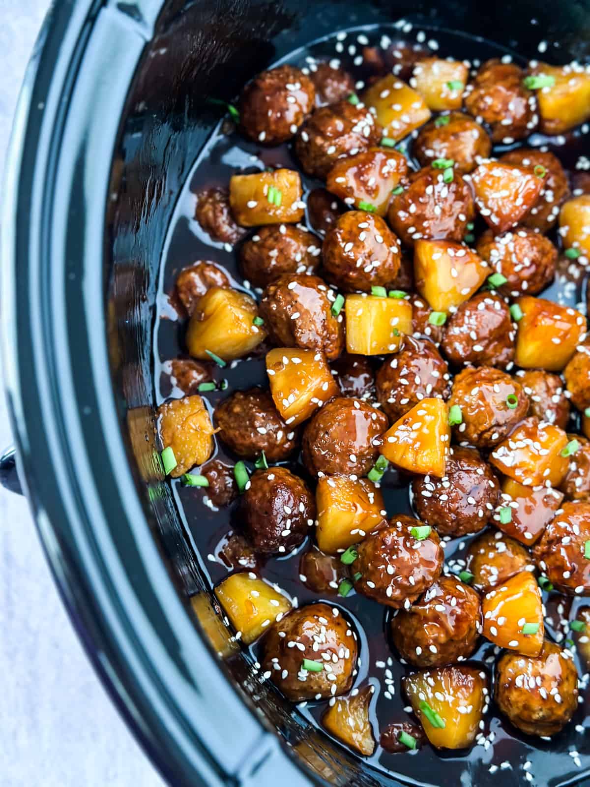 close up of the meatballs and pineapple in a slow cooker