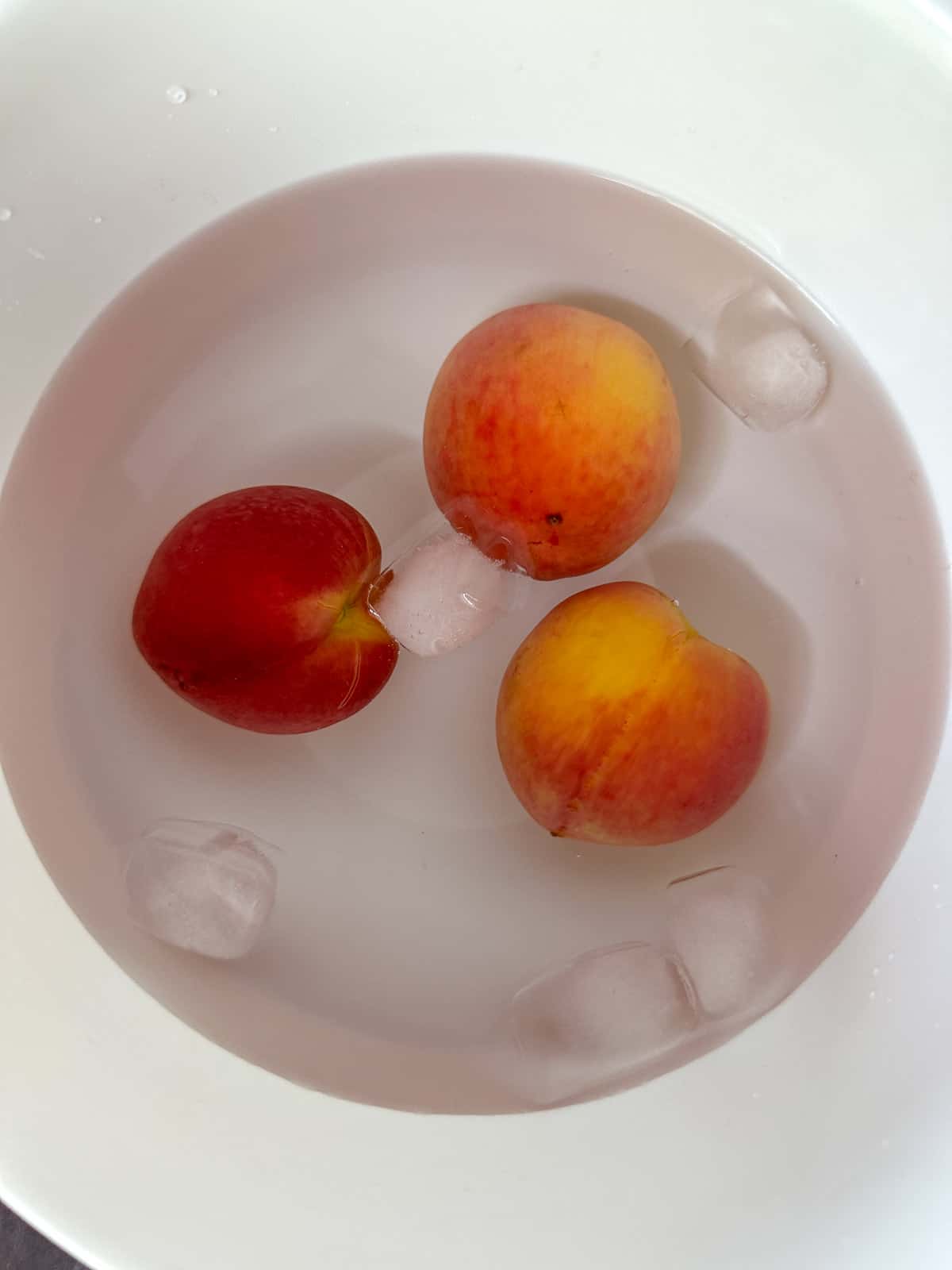 3 peaches in an ice water bath