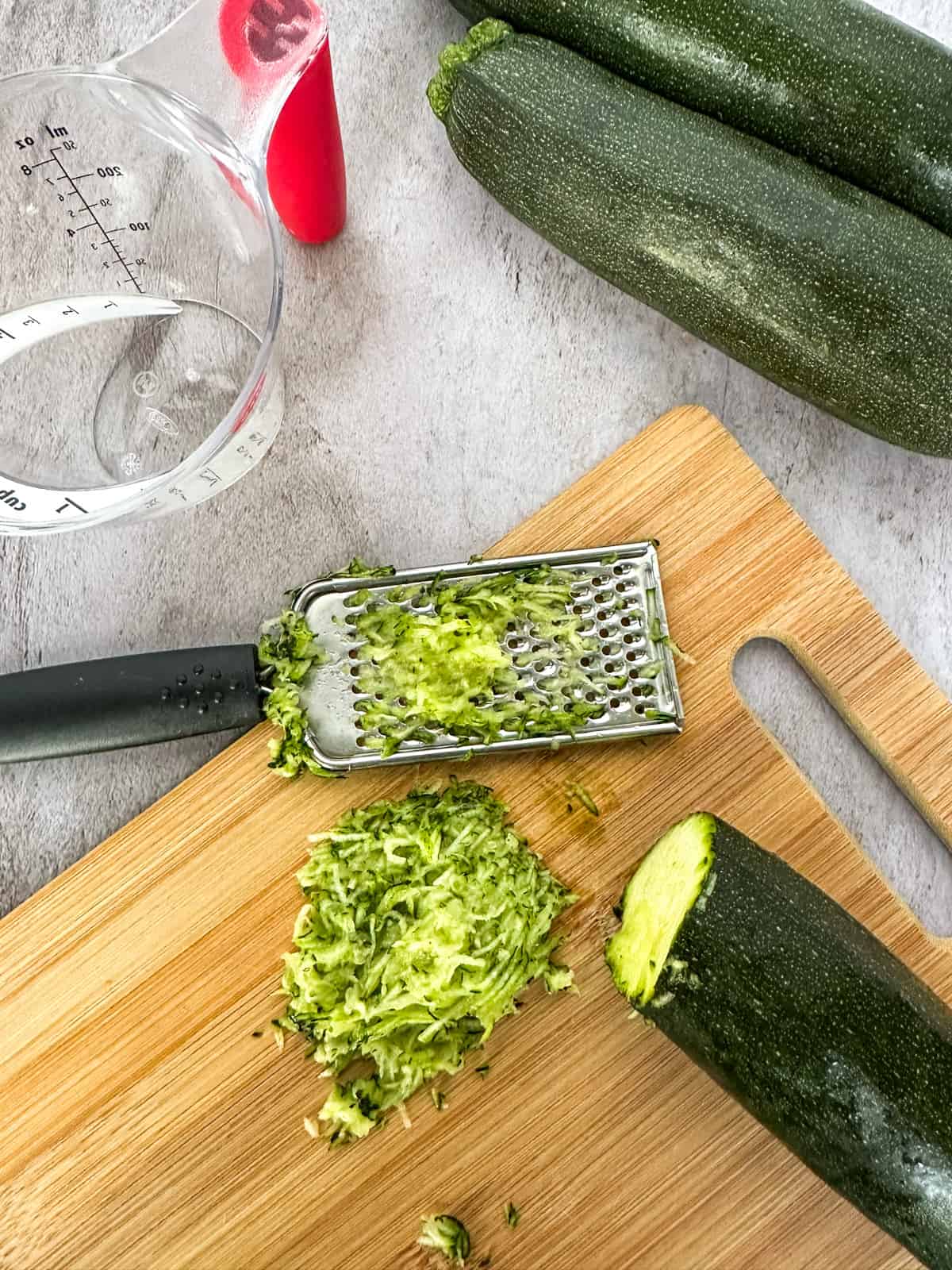 shredding zucchini on a cutting board
