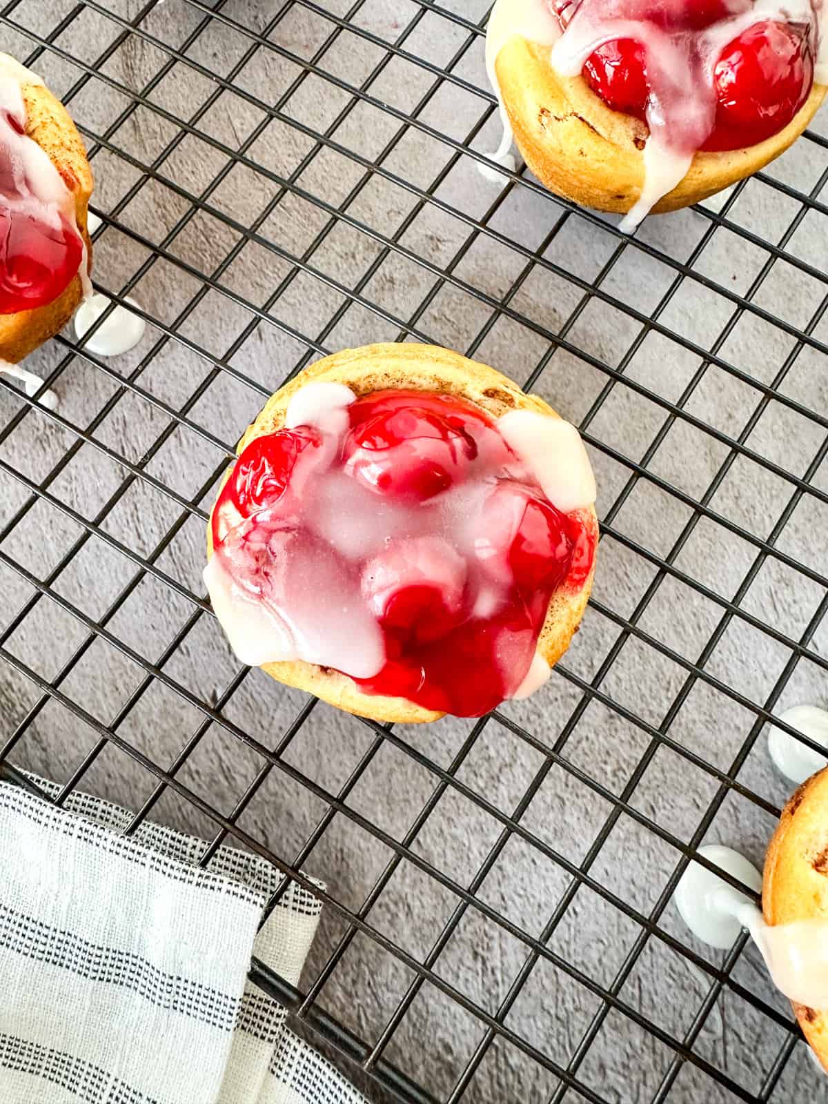 A Cherry Pie cup with icing drizzled over the top on a cooling rack.