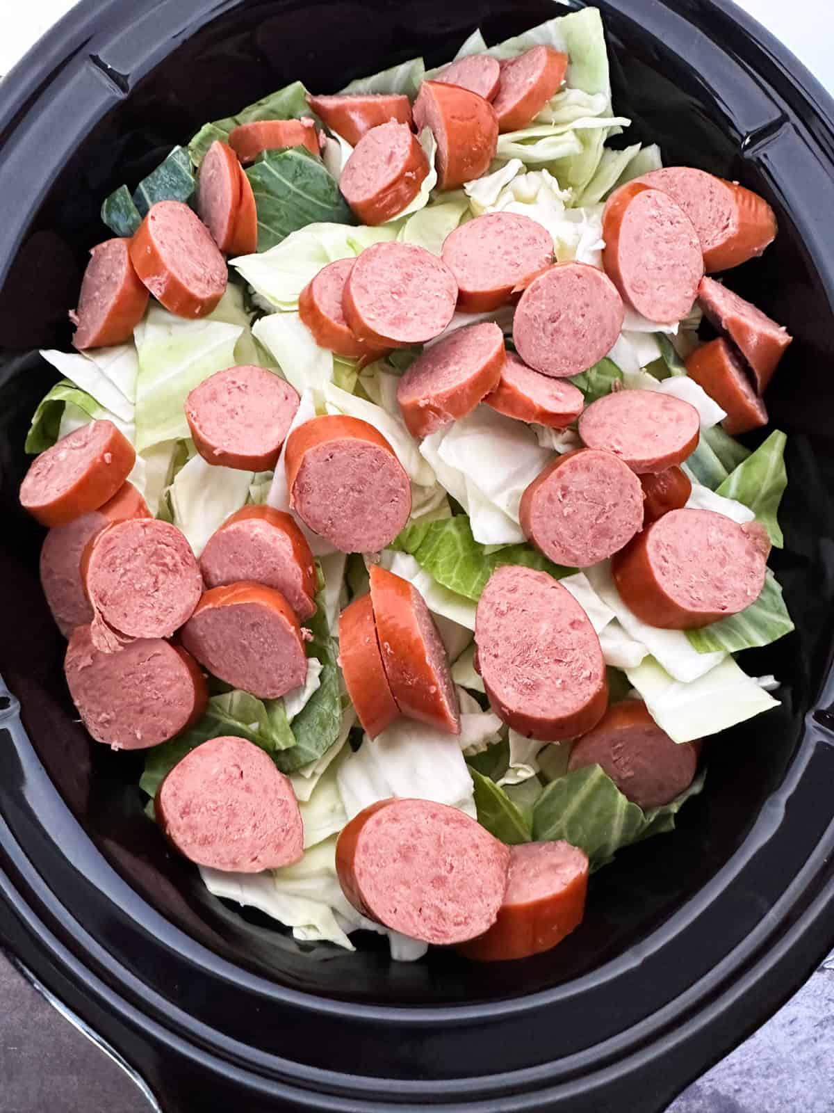Potatoes, carrots, onion, cabbage, and sliced smoked sausage in a crock pot.