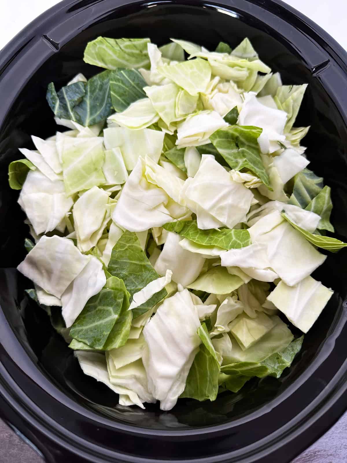 Potatoes, carrots, onion, and cabbage in a crock pot.