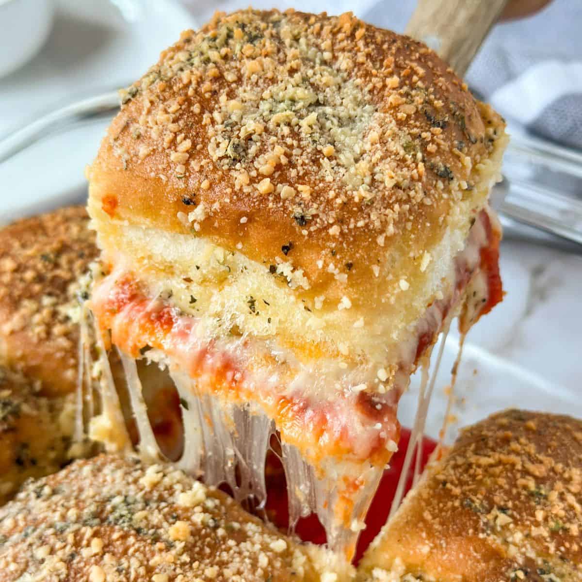 A pizza slider on a spatula being pulled from a pan.