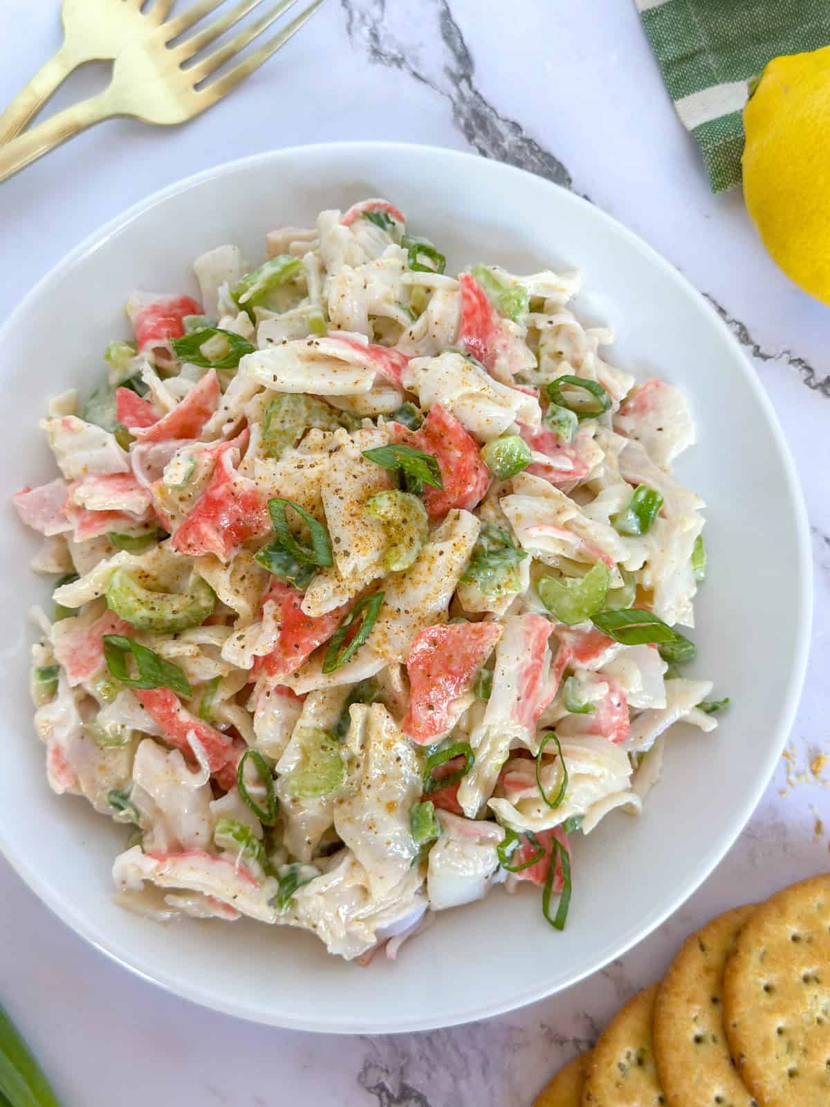 Cajun Crab Salad on a plate with a lemon and crackers next to it.