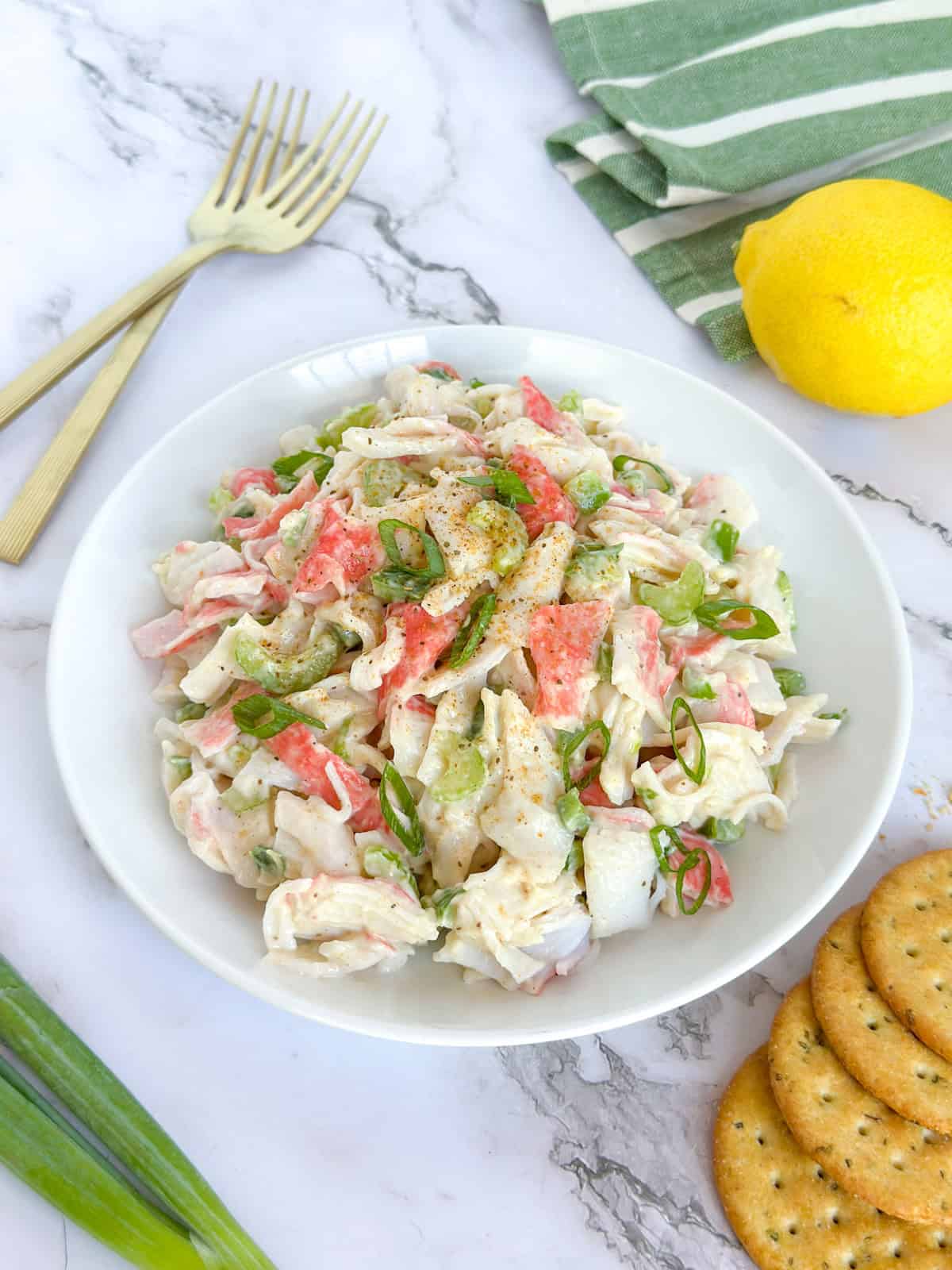 Cajun Crab Salad on a plate with a fork, a lemon and crackers next to it.