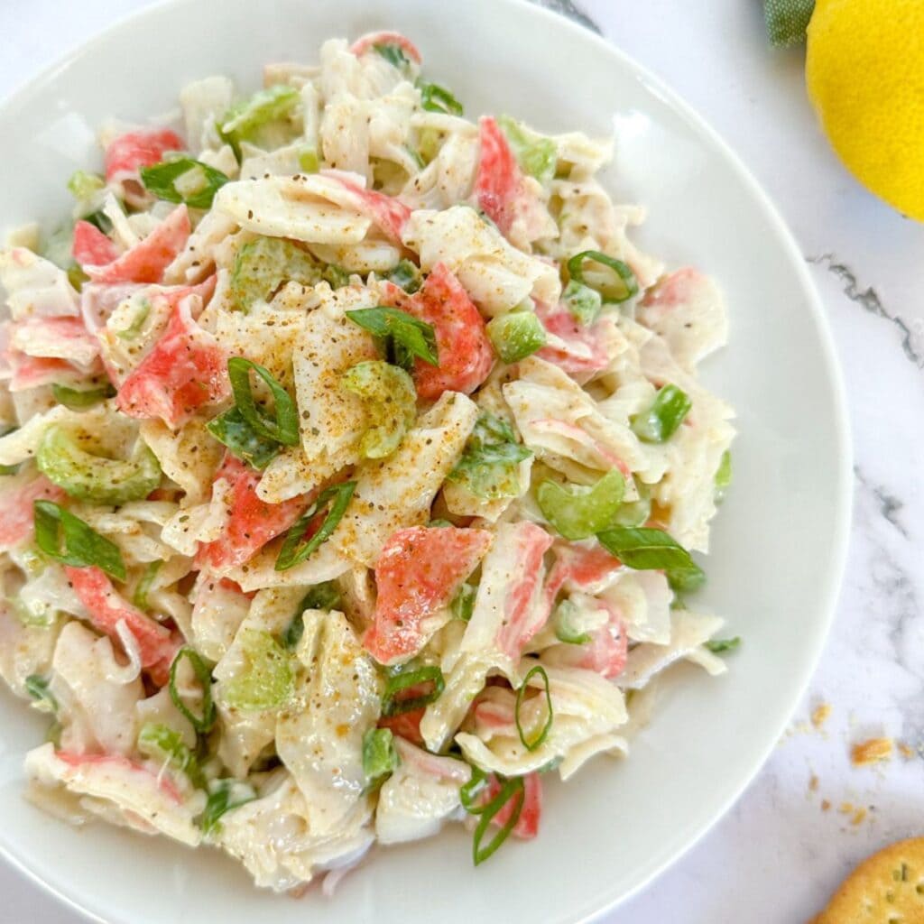 Cajun Crab Salad on a plate with a lemon and crackers next to it.