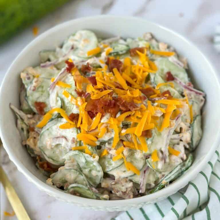 A bowl of Jalapeño Popper Cucumber and Onion Salad with extra cheese and bacon on top.