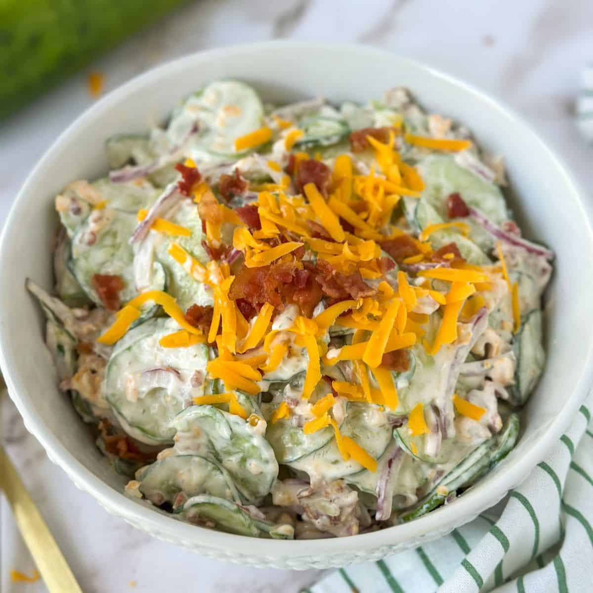 A bowl of Jalapeño Popper Cucumber and Onion Salad with extra cheese and bacon on top.