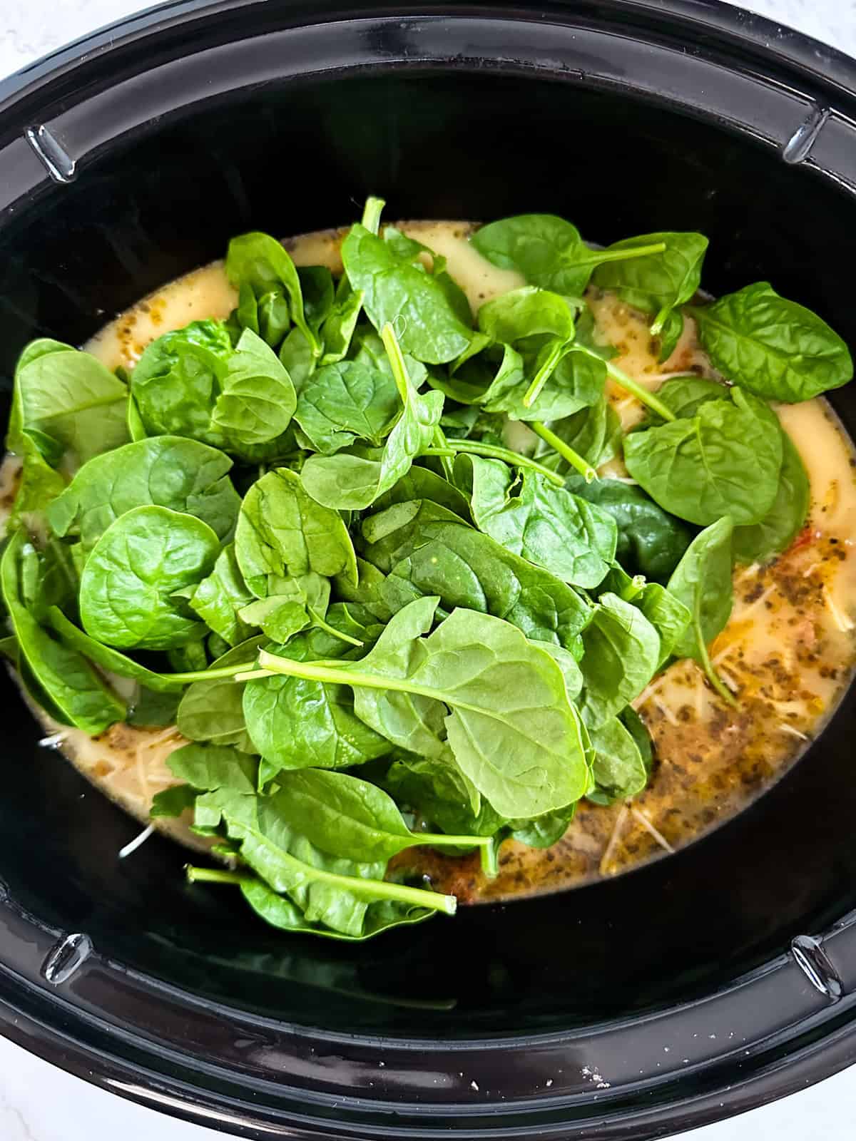 Spinach on top of the soup in the slow cooker.