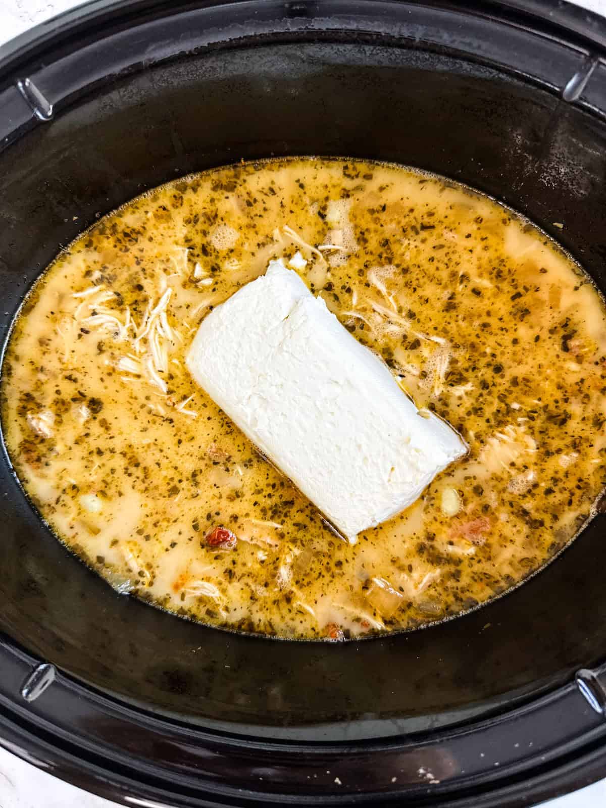 A block of cream cheese on top of the soup.